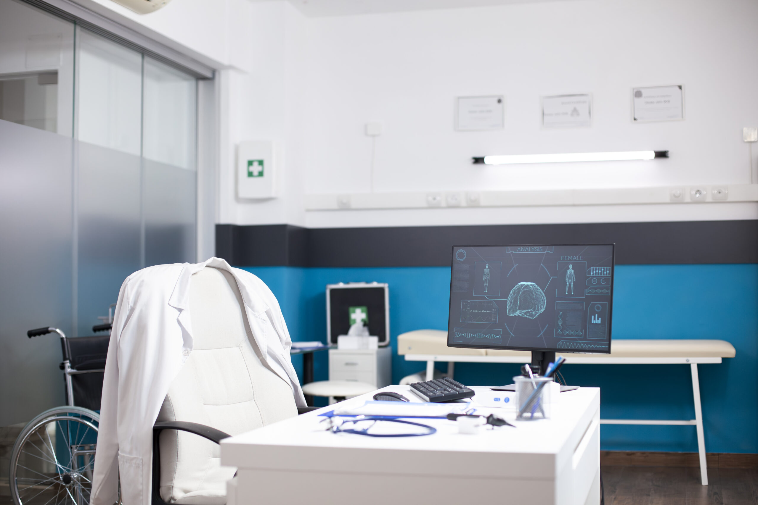 In doctors office, desktop monitor displays female brain and body imaging data, framed by diagnostic tools and medical files. The empty workspace is geared toward precise health assessments.